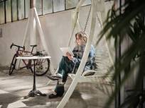 Eine Frau auf einer Hollywood-Schaukel, die ein Tablet bedient.