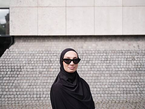 Bild von Lexware: Frau mit schwarzem Kopftuch und Sonnenbrille schaut l&auml;chelnd in die Kamera